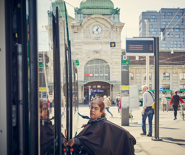 Une femme en fauteuil électrique monte seule dans un tram. 